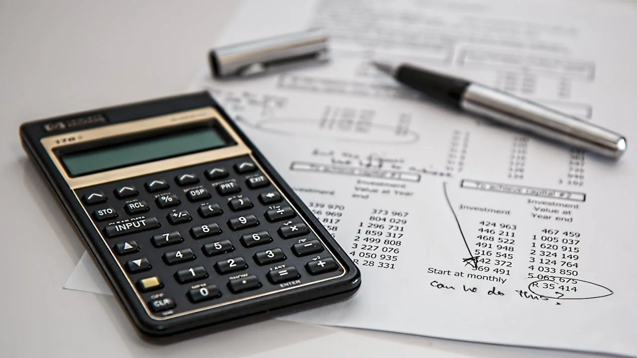 A calculator on top of a paper and a pen