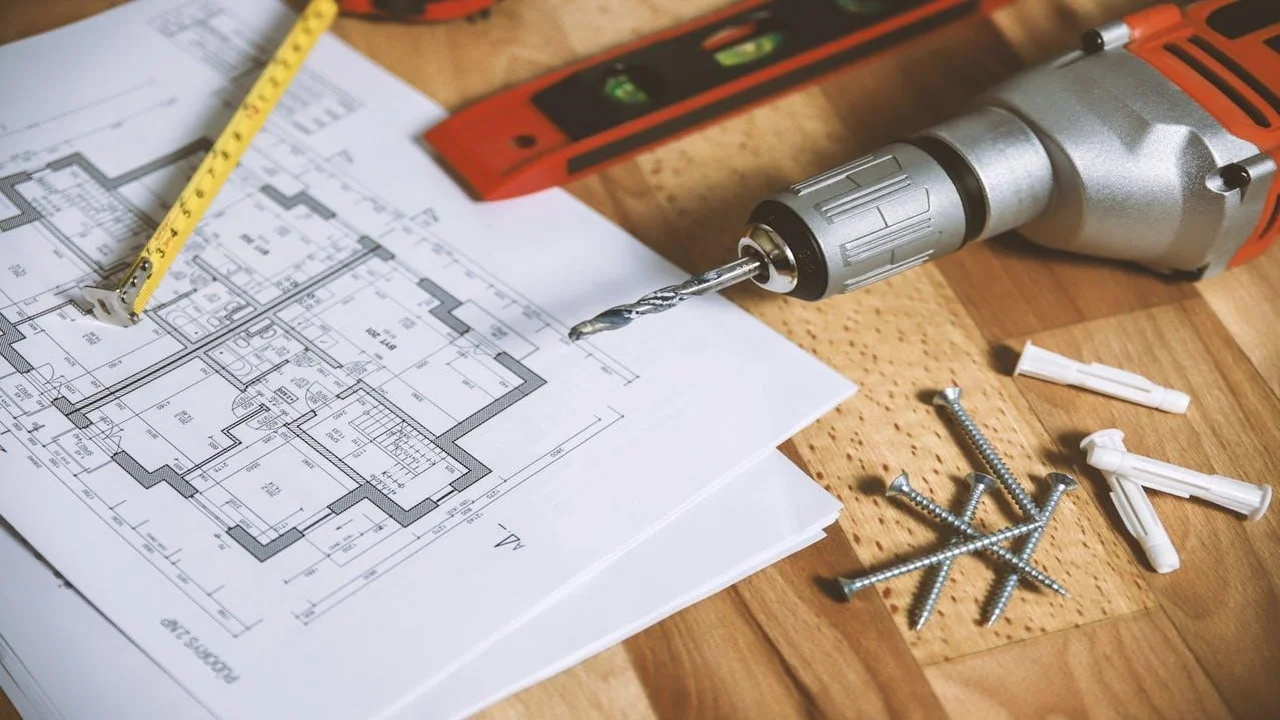 A floor plan right next to a drill and some screws